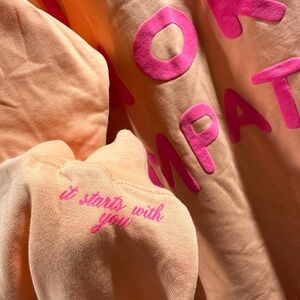 Mayfair Group 'The World Needs More Empathy Peach Fuzz
Crewneck' L/XL